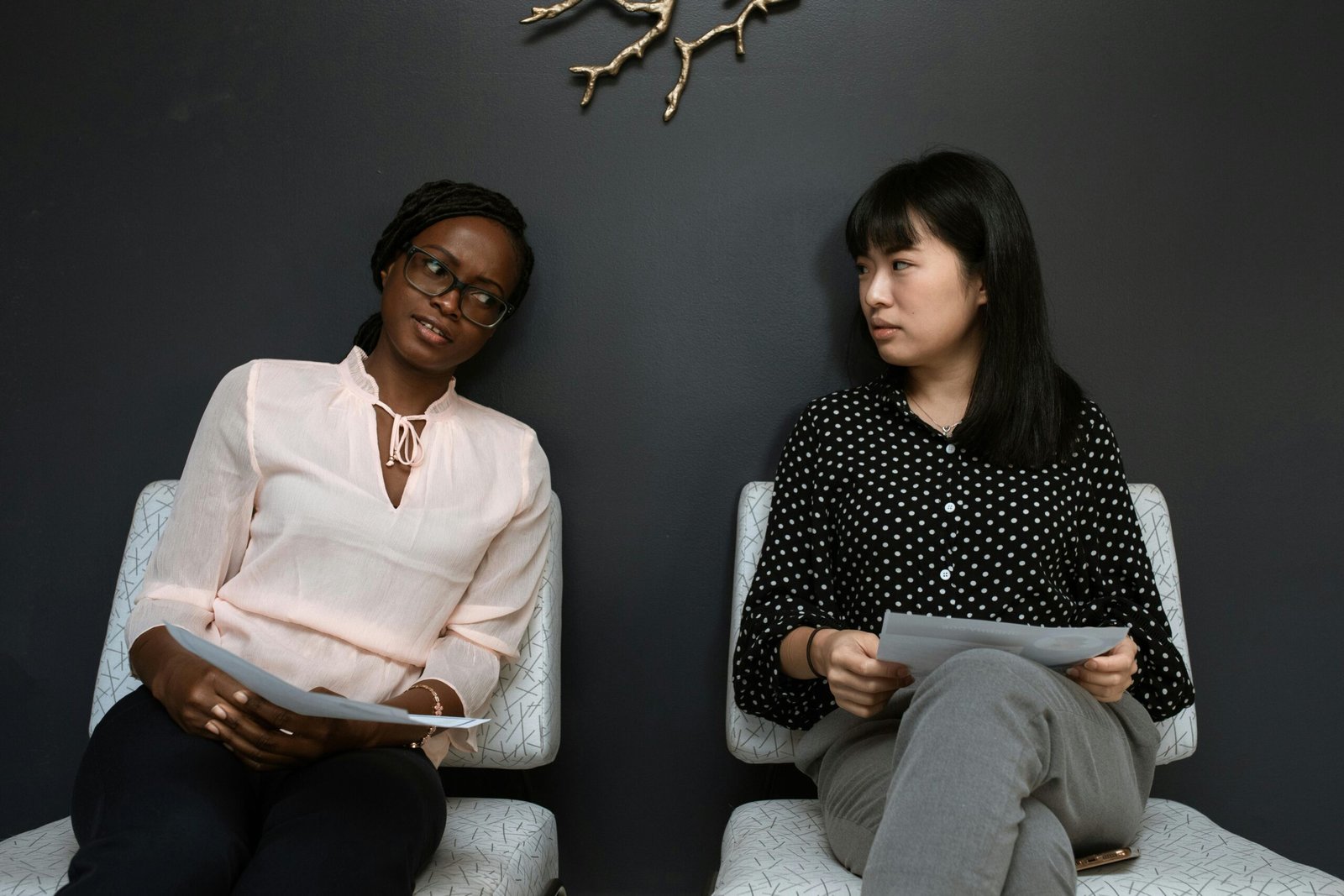 Two businesswomen having a discussion in a sleek, modern office setting.