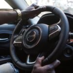 Close-up of a man's hands on a luxury car steering wheel highlighting modern interior.