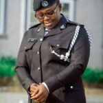 Smiling African policewoman in uniform posing outdoors, summer day.