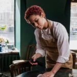 Young waitress cleans a table in a cozy café, capturing the essence of service and hospitality.