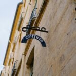 A close-up of a vintage hair salon sign on a classic stone building in an urban environment.